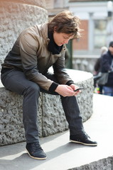 Portrait of young guy sending message with smartphone