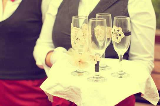 waiter holding a plate with 4 empty champagne glasses