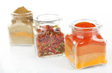 Different kinds of spices in glass bottles isolated on white