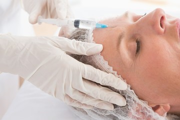 Woman receiving cosmetic injection on her forehead