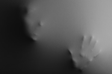 Human face with hand pressing through fabric as horror