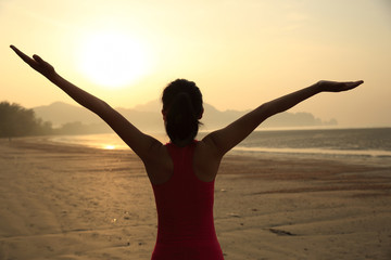 Fototapeta premium cheering woman open arms at sunrise beach