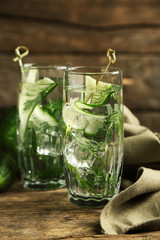 Glasses with fresh organic cucumber water on wooden table
