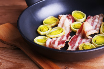 Strips of bacon with sliced shallot in pan