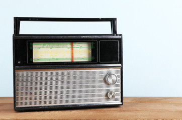 Retro radio on wooden table on light colorful background