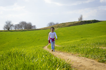 Naklejka na ściany i meble Niña corriendo y caminando feliz por el camino en el campo