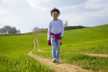 Niña corriendo y caminando feliz por el camino en el campo