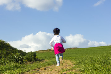 Niña corriendo y caminando feliz por el camino en el campo