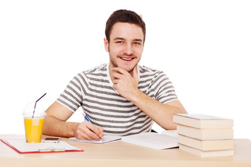 Young man sitting at the table with a pile of books