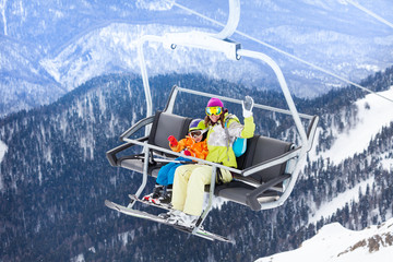Happy boy with mother sit on skilift ropeway chair