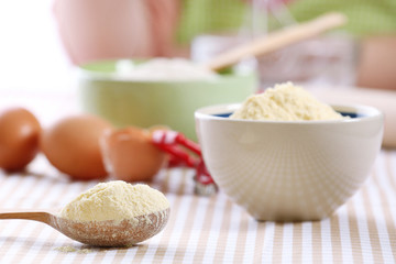 Cornmeal in bowl with wooden spoon on table close up