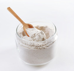 Glass bowl with flour and wooden spoon isolated on white