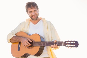 Happy man smiling at camera playing guitar