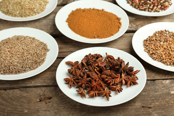 Different spices on plates, on old wooden table