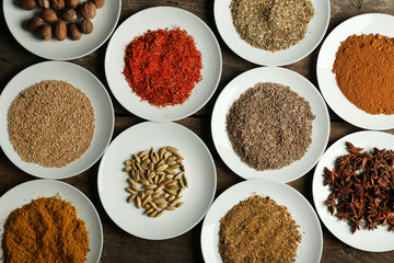 Different spices on plates, on old wooden table