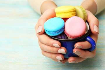 Cup of tasty colorful macaroons in female hands