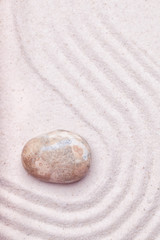 A marble rock  and wave pattern in the sand of a zen garden