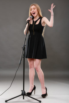 Portrait of a beautiful blonde young woman singing into micropho