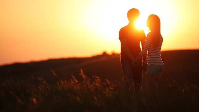man and woman kissing at sunset