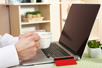 Man holding credit card and working on laptop