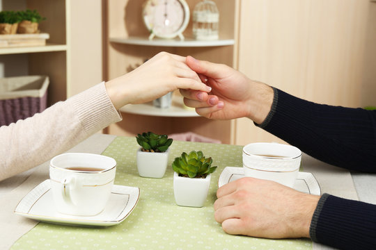 Female and male hands with cups of tea, close-up,