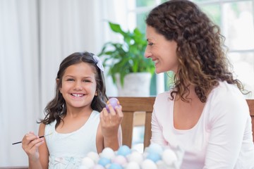 Happy mother and daughter painting easter eggs