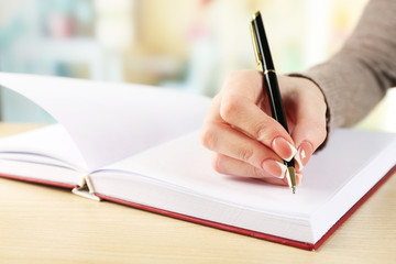 Female hand with pen writing on notebook, closeup