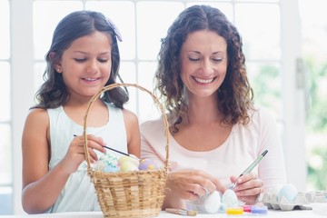Happy mother and daughter painting easter eggs