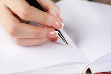 Female hand with pen writing on diary, closeup