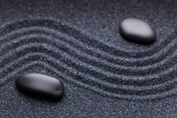 Zen garden with a wave lines in the sand with irregular black st