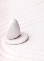 Fototapeta na wymiar Balancing silky white stones in black grain sand with wavy patte