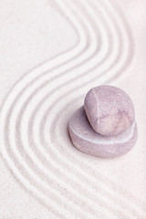 A stack of stones in the fine sand of the zen garden with wavy p