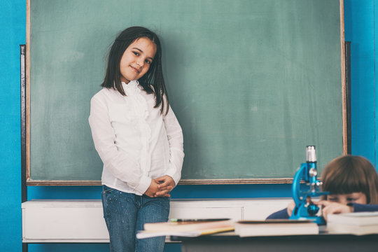 Cute Indian schoolgirl with Caucasian friend in a classroom.
