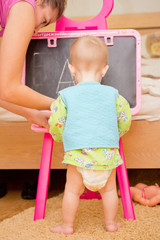 Baby writes letters on a school blackboard