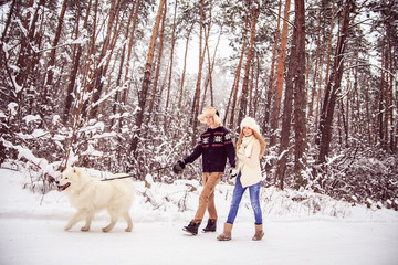 Fototapeta na wymiar boy and girl in winter walks in the woods with a white dog