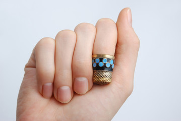 hand, a thimble on her finger