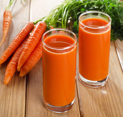 Glasses of fresh carrot juice on wooden table