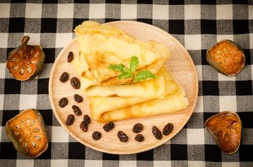 Pancake with raisin on wooden plate