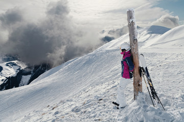 Young woman skier against a dramatic winter mountains background