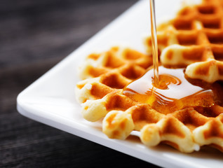 Honey pouring on a fresh waffles - obrazy, fototapety, plakaty