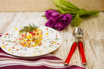 crab salad on a plate and a bouquet of tulips on a table