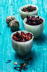 variety of dry tea leaves in jade stacks on wooden background