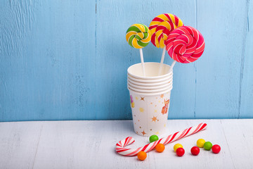cups and lollipop on the blue wooden background