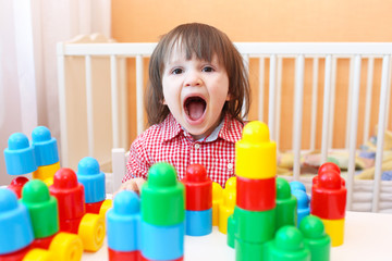 Happy little boy playing plastic blocks at home