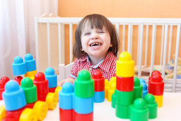 Funny smiling little boy playing plastic blocks