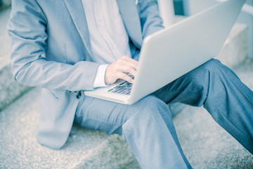 Businessman using laptop pc. He is sitting on a stairs.