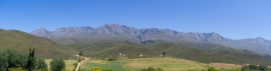 Panoramic farm landscape with high mountains and fields