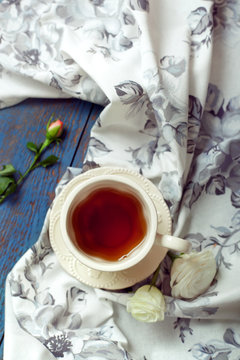 Cup of tea set with a tea towel and roses on a wooden