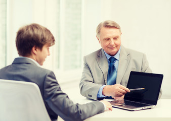 older man and young man with laptop computer