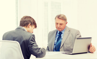 older man and young man signing papers in office